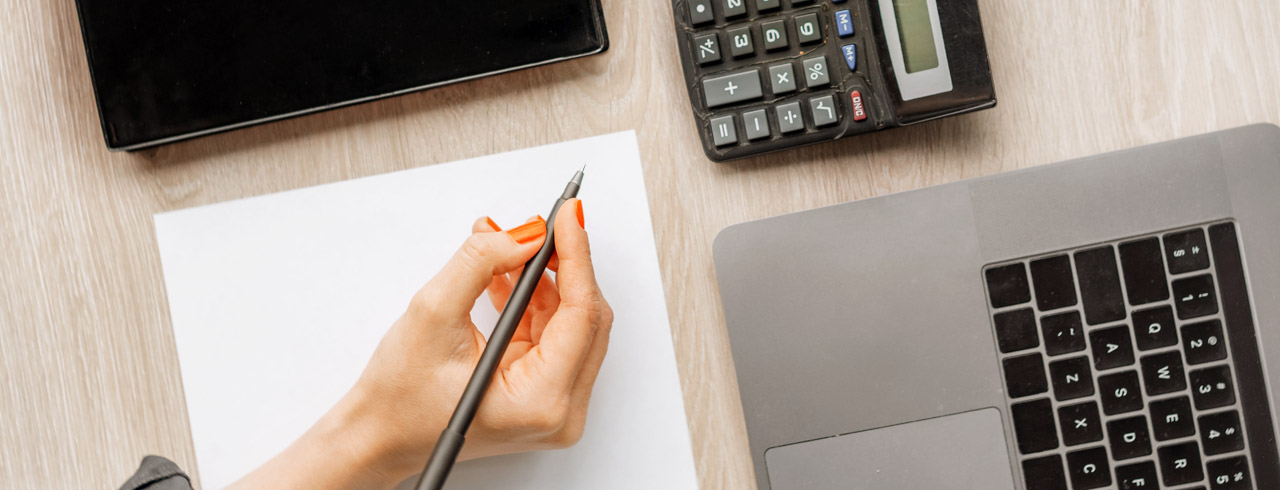 Рабочее место бухгалтера: ноутбук, калькулятор и блокнот.